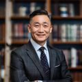 探花网创始人陈维的专业形象照，西装笔挺、面带自信微笑，背景为探花网办公室书架